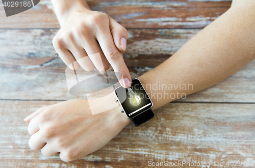 Image of close up of hands with light bulb on smart watch