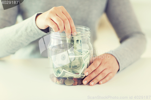 Image of close up of woman hands and dollar money in jar