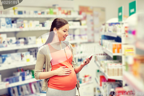 Image of happy pregnant woman with smartphone at pharmacy
