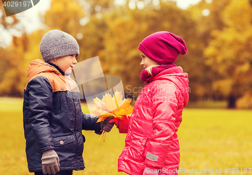 Image of little boy giving autumn maple leaves to girl