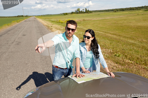 Image of happy man and woman with road map on car hood