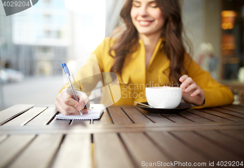 Image of happy woman with notebook and cappucino at cafe
