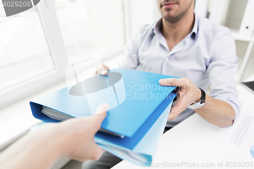 Image of close up of businessman taking folders from hand