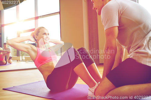 Image of woman with personal trainer doing sit ups in gym