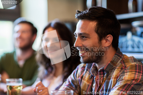 Image of happy friends drinking beer at bar or pub