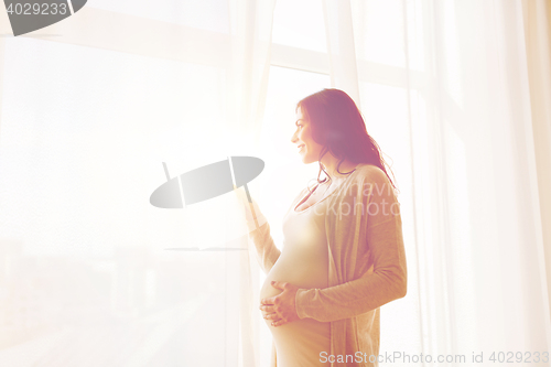 Image of close up of happy pregnant woman looking to window