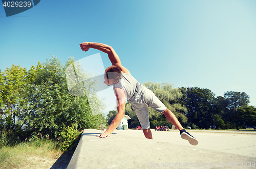 Image of sporty young man jumping in summer park