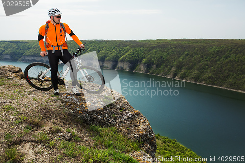 Image of Cyclist in Orange Wear Riding the Bike above River