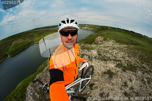 Image of Cyclist in Orange Wear Riding the Bike above River