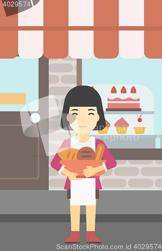 Image of Baker holding basket with bakery products.