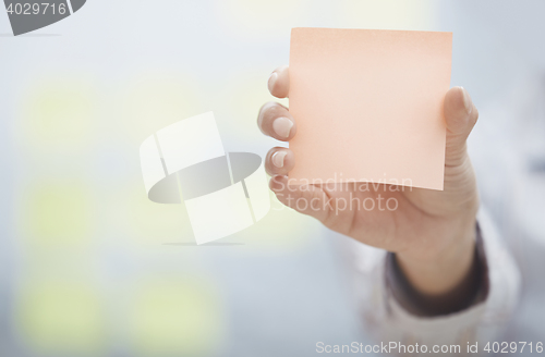 Image of Hand of woman holding sticky note with empty space