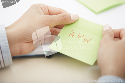 Image of Hands holding sticky note with internet address