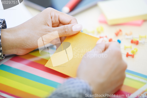 Image of Woman at office holding adhesive note