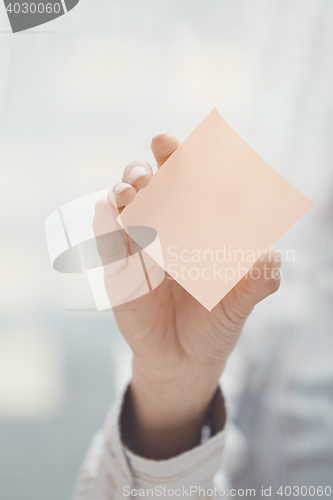 Image of Hand of woman holding sticky note with empty space