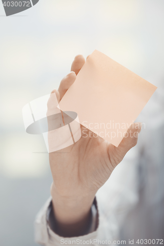 Image of Hand of woman holding sticky note with empty space