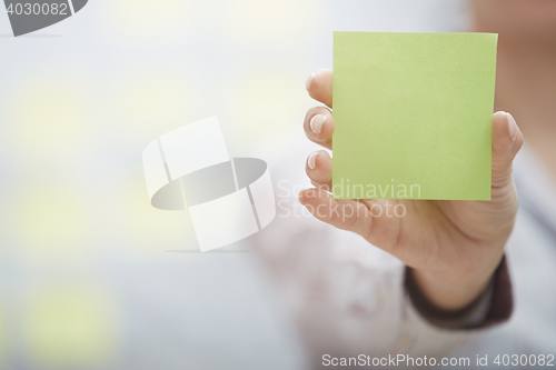 Image of Hand of woman holding sticky note with empty space