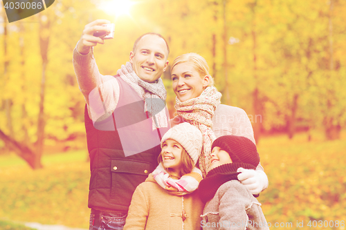 Image of happy family with camera in autumn park