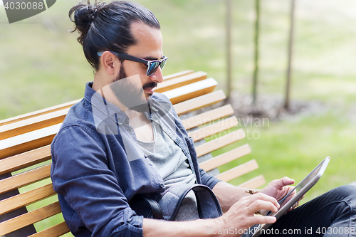 Image of man with tablet pc sitting on city street bench