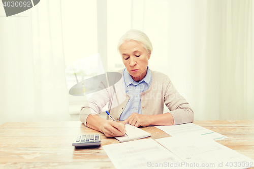 Image of senior woman with papers and calculator at home