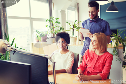 Image of happy creative team with computer in office