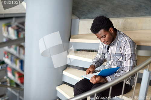 Image of african student boy or man reading book at library
