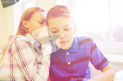 Image of smiling schoolgirl whispering to classmate ear