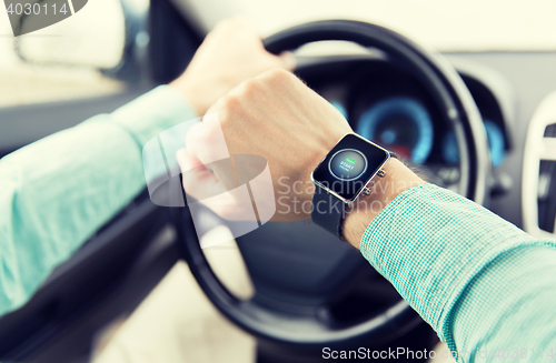 Image of hands with starter icon on smartwatch driving car