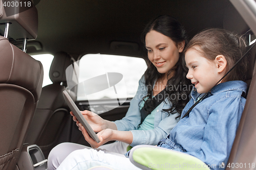 Image of happy family with tablet pc driving in car