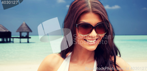 Image of smiling young woman with sunglasses on beach