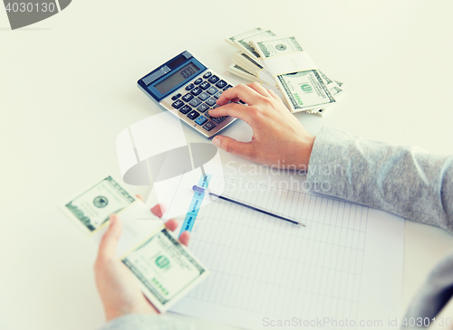 Image of close up of hands counting money with calculator