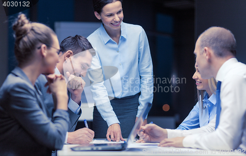 Image of smiling female boss talking to business team