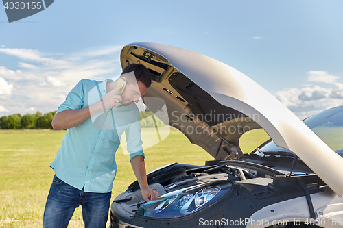 Image of man with broken car calling on smartphone