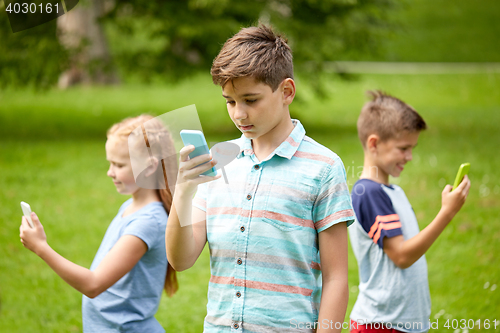 Image of kids with smartphones playing game in summer park