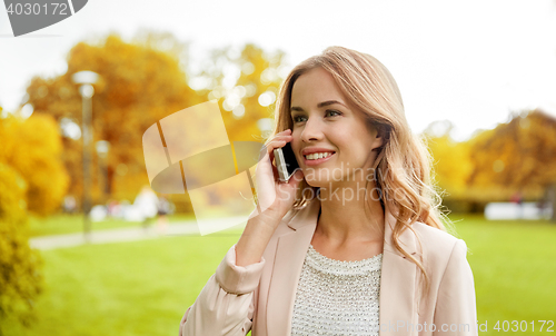 Image of smiling young woman calling on smartphone outdoors