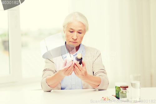 Image of senior woman with medicine jars at home