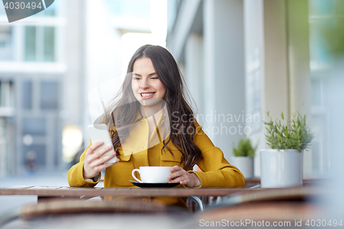 Image of happy woman texting on smartphone at city cafe