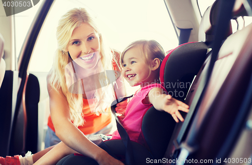 Image of happy mother fastening child with car seat belt