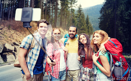 Image of friends with backpack taking selfie by smartphone