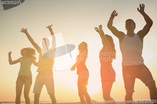 Image of smiling friends dancing on summer beach