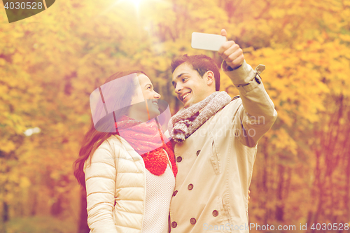 Image of smiling couple hugging in autumn park