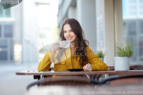 Image of happy woman drinking cocoa at city street cafe