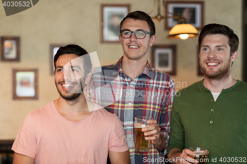 Image of happy male friends drinking beer at bar or pub