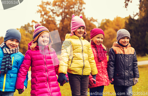 Image of happy children holding hands in autumn park