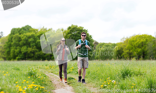 Image of happy couple with backpacks hiking outdoors