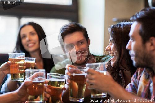 Image of happy friends drinking beer at bar or pub