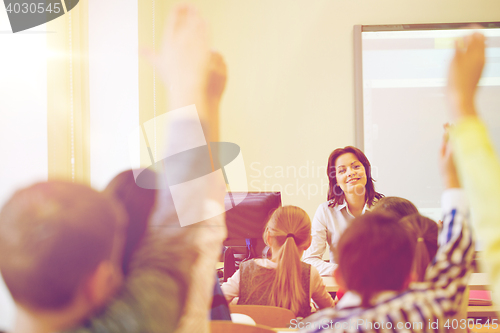 Image of group of school kids raising hands in classroom