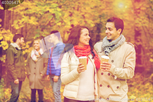 Image of group of smiling friend with coffee cups in park