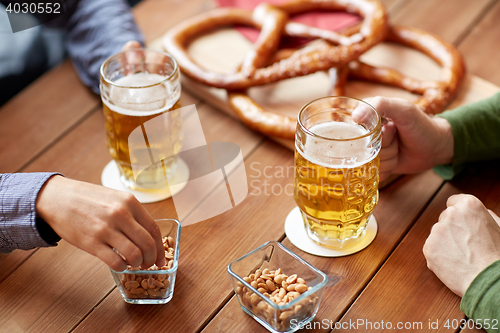 Image of close up of hands with beer mugs at bar or pub