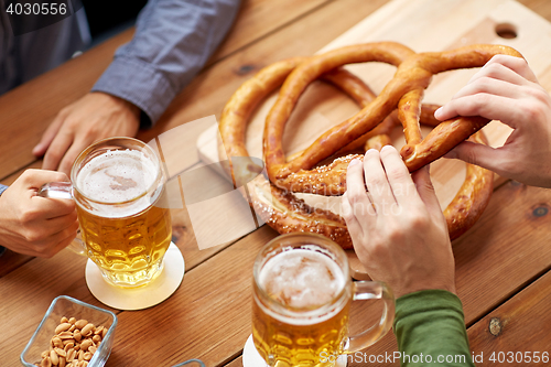 Image of close up of men drinking beer with pretzels at pub