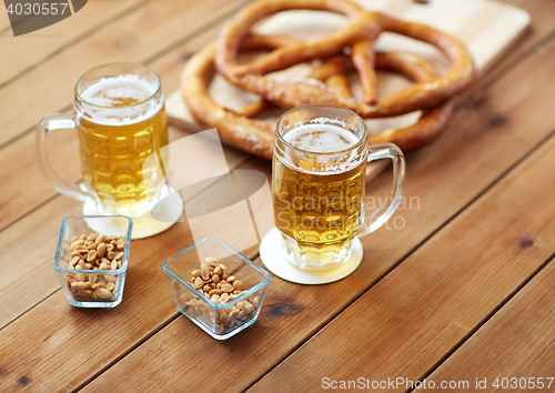 Image of close up of beer, pretzels and peanuts on table